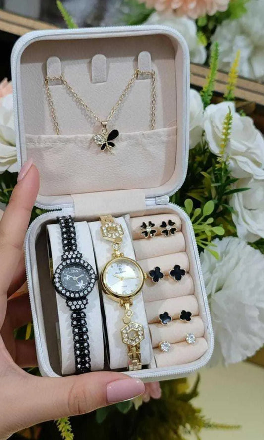 Compact jewelry box with gold and black watches, butterfly necklace, and matching stud earrings on floral background