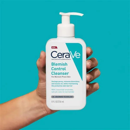 Hand holding CeraVe Blemish Control Cleanser bottle on blue background, skincare for acne-prone skin