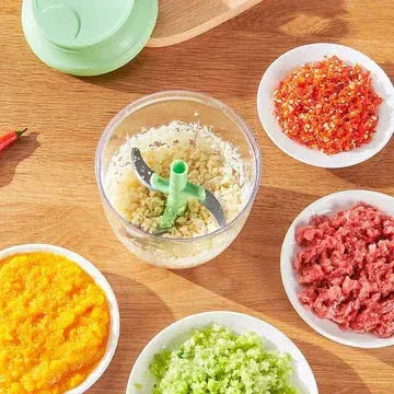 Food processor chopping garlic surrounded by bowls of minced vegetables and ground meat on wooden surface