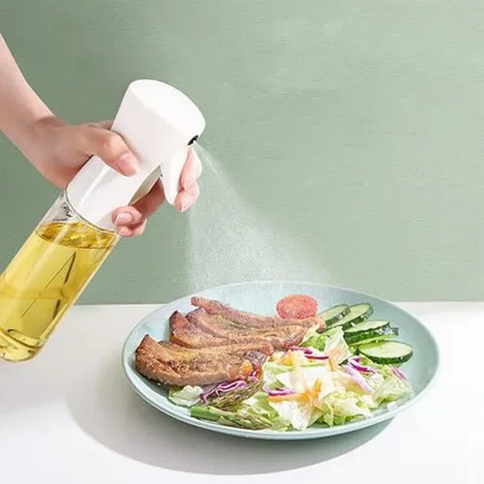 Hand using oil spray bottle to mist salad and meat on plate, sunehri store