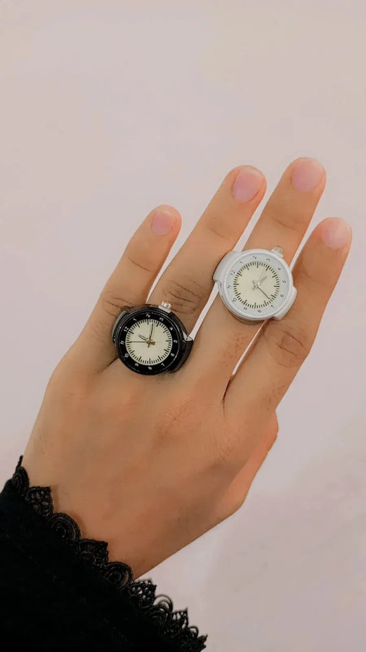 Hand wearing two finger rings featuring mini elastic strap quartz watch faces in black and white